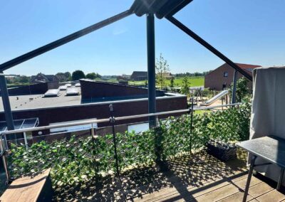 Blick vom Balkon der Ferienwohnung in Ascheberg im Münsterland auf weites Land mit viel grün und Bäumen. Ein Tisch und eine Bank laden zum Entspannen ein.