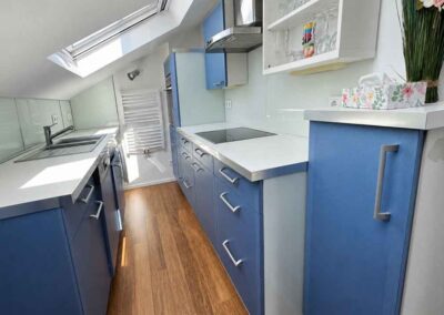 Die umfangreich ausgestattete Küchenzeile in Weiß mit blauen Türen ist mit allem ausgestattet, was in der Ferienwohnung nichts vermissen lässt. Herd, Backofen in Schulterhöhe, Spülmaschine, Abzug und vieles mer
